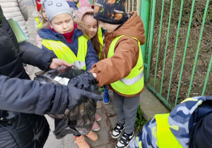 Przedszkolaki wrzucają śmieci do worka