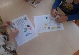 Dzieci rysują dodatkowe elementy na kartkach