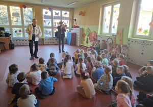 Przedszkolaki słuchają jak Pan Jacek gra na trąbce