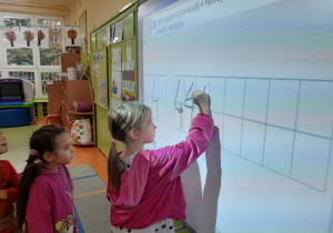 Przedszkolaki wykonują ćwiczenia na tablicy interaktywnej
