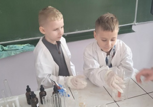 Chłopcy wykonują doświadczenie chemiczne z wykorzystaniem cukru pudru