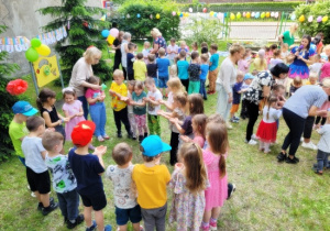 Ciocie wysypują kolorowe holi na rączki dzieci