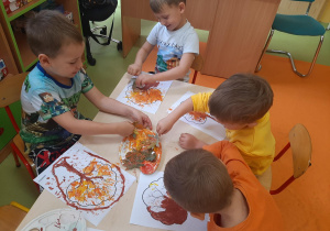 Chłopcy odbijają liście w farbie