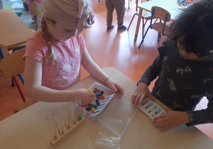 Dziewczynka układa koraliki do probówek według wzoru