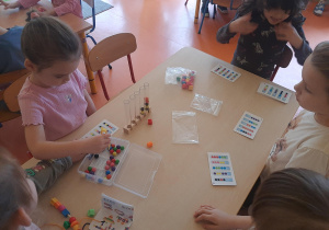 Dziewczynka za pomocą pęsety układa koraliki