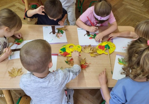 Praca indywidualna dzieci - tworzenie korony drzewa za pomocą stemplowania pomalowanymi liśćmi