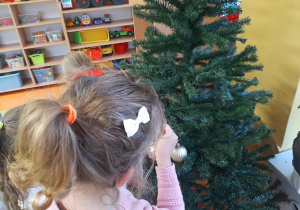Dzieci wieszają bombki na choince