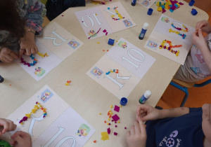 Dzieci ozdabiają literę i cyfrę kulkami bibuły